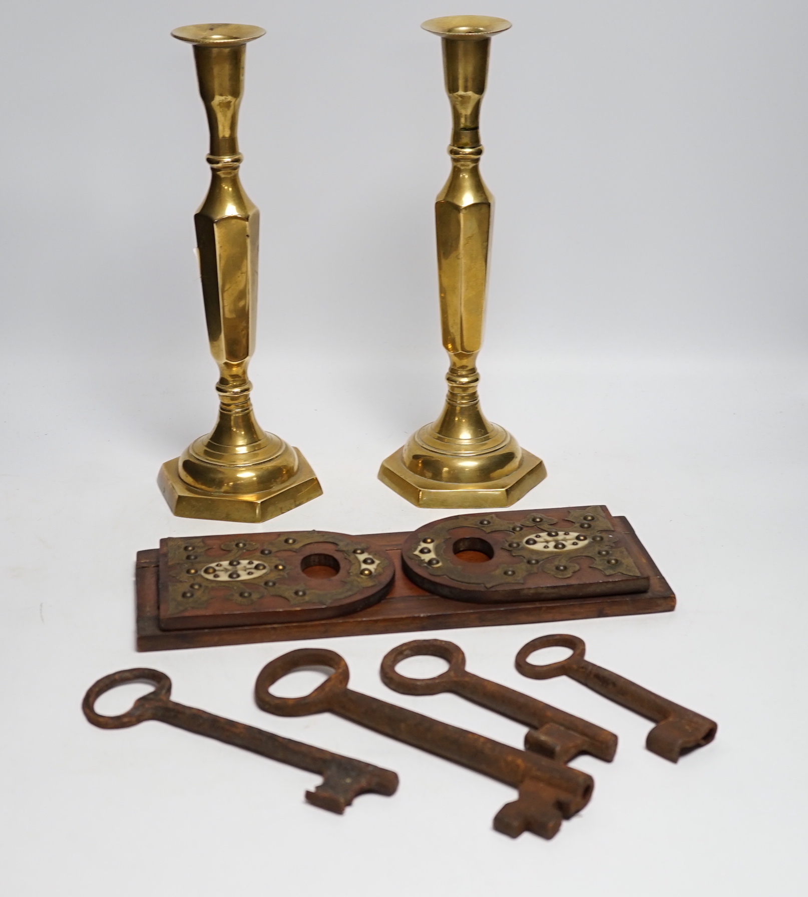 A group of mixed metalware including a pair of brass candlesticks, a brass bound book slide, iron keys, etc.